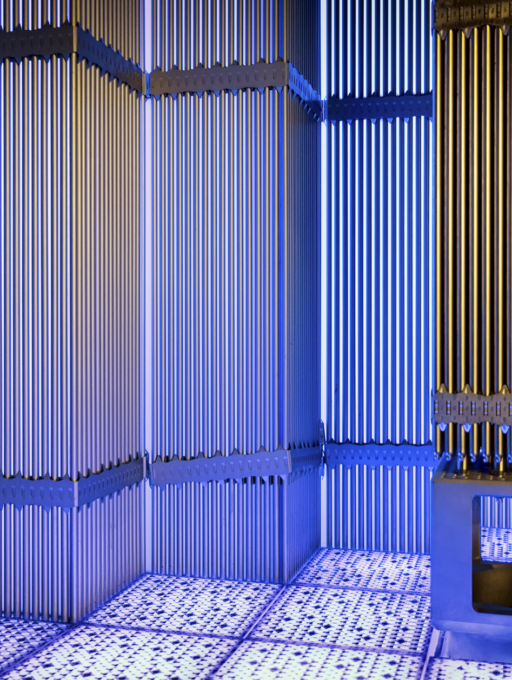 Interior of a nuclear reactor with vertical fuel assemblies illuminated in blue and gold light