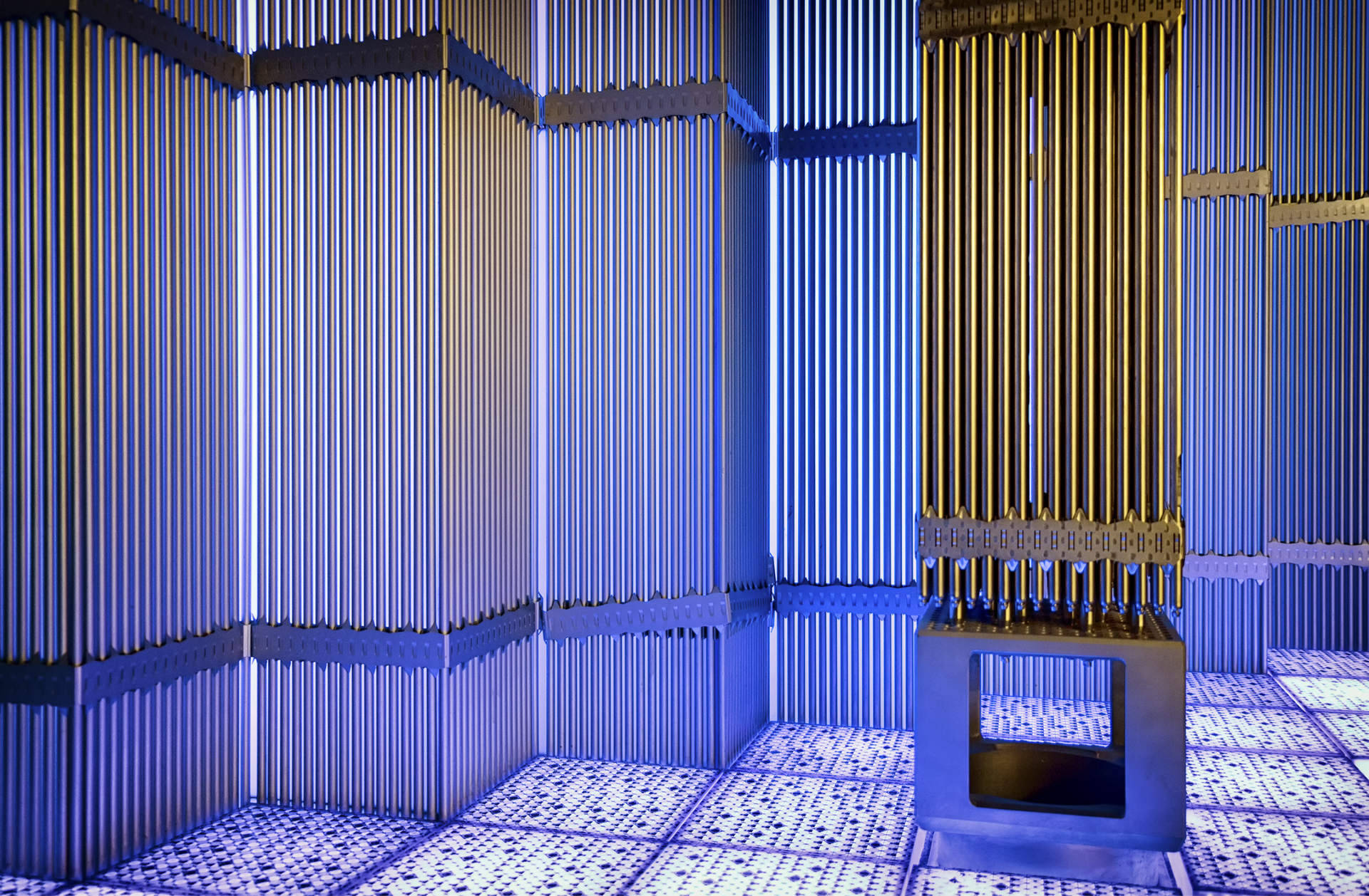 Interior of a nuclear reactor with vertical fuel assemblies illuminated in blue and gold light