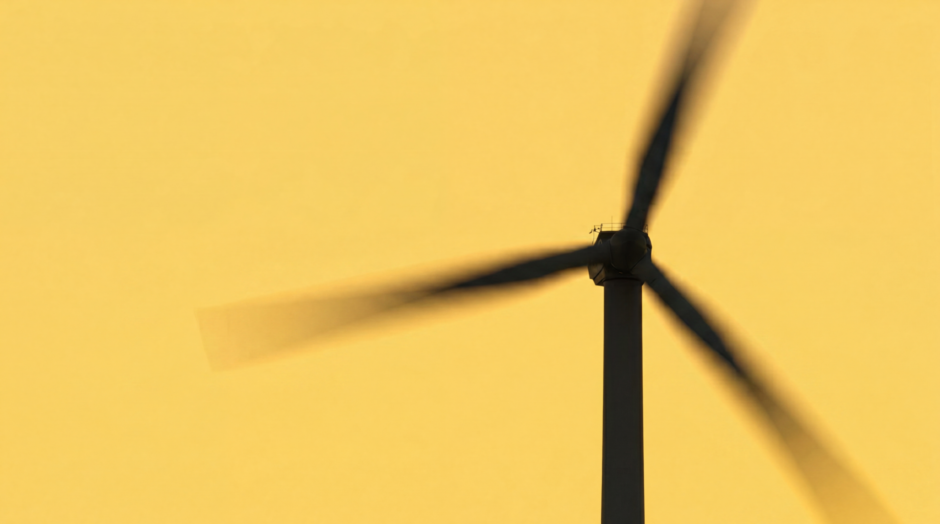 Wind turbine with motion-blurred blades against a golden sky