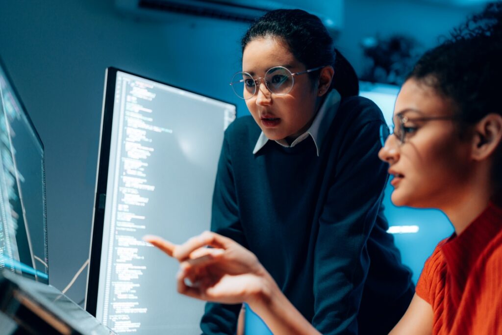 Two students reviewing computer code on a screen