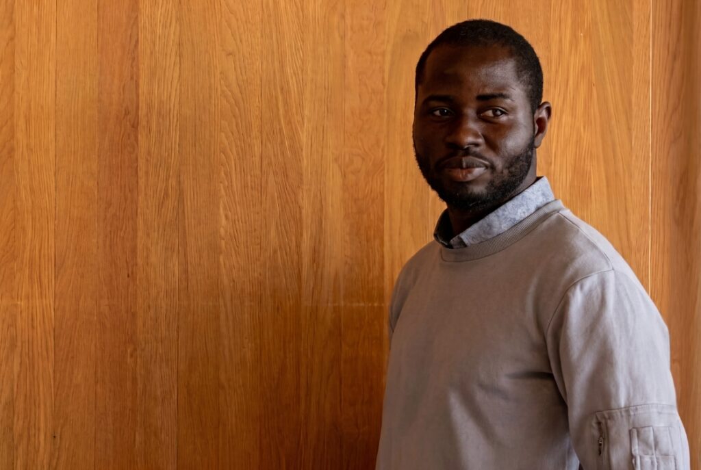 Student standing against a wooden wall
