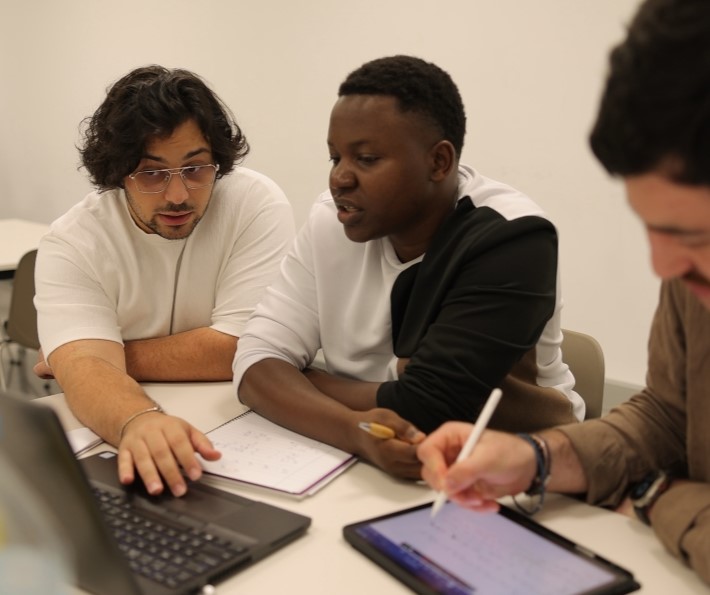 Masters+ students working together on a project with a laptop and tablet