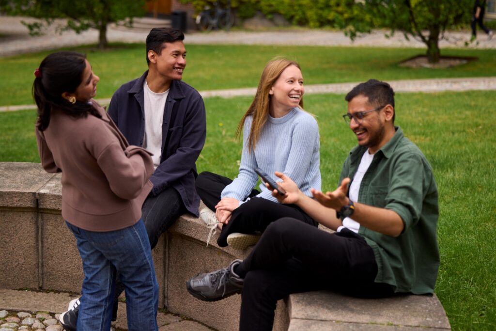 Four students talking together outdoors on a university campus