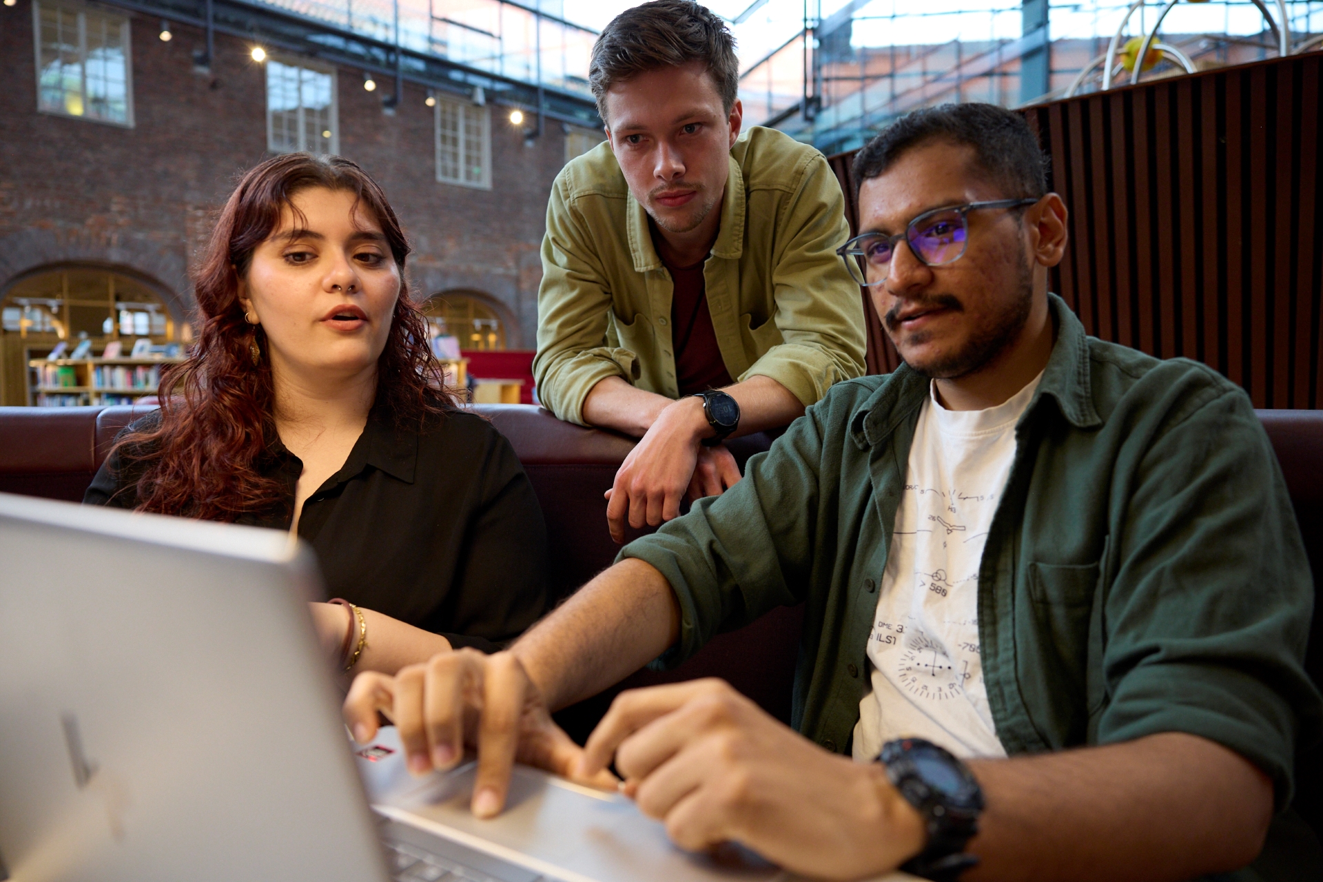 Three students collaborating around a laptop