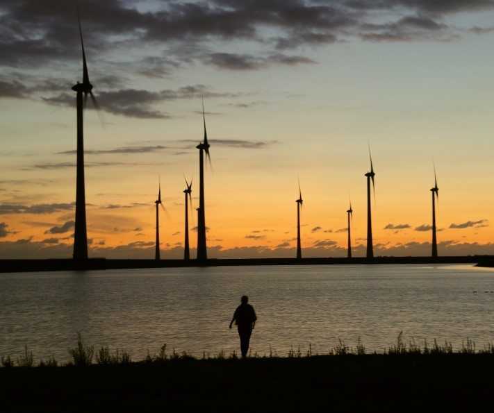 Wind turbines at sunset with a person in the foreground